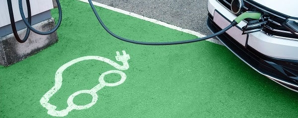 Electric car icon printed on green floor in electric vehicle charging station with car plugged on