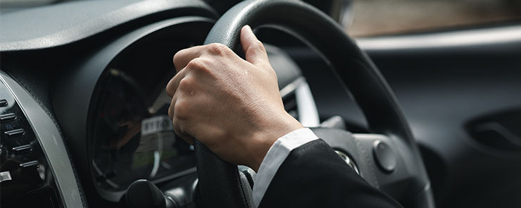 A man in a suit is driving a car to work, he is driving a car to work at the company. Vehicle driving concept.