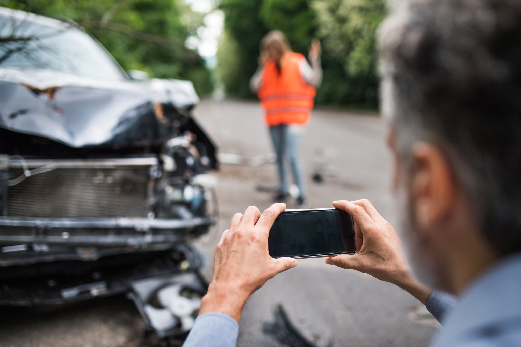 Unrecognizable man taking pictures of a broken car after an accident. Assicurazione Kasko: