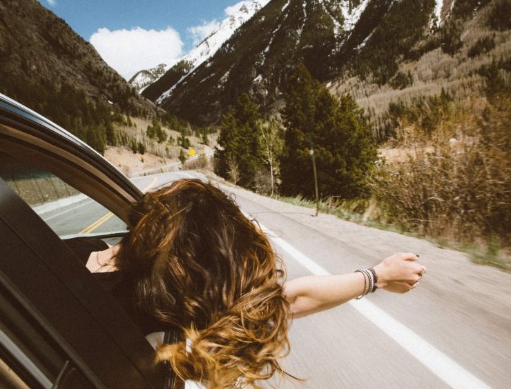 donna spensierata in auto in una strada di montagna