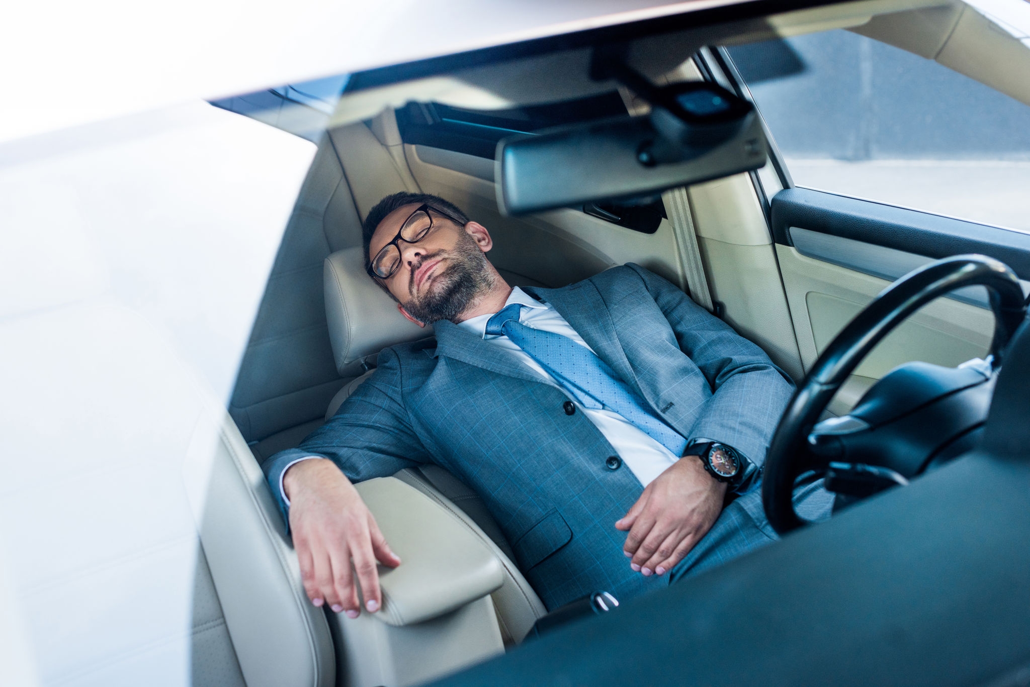 tired businessman in eyeglasses sleeping in car Dormire in auto